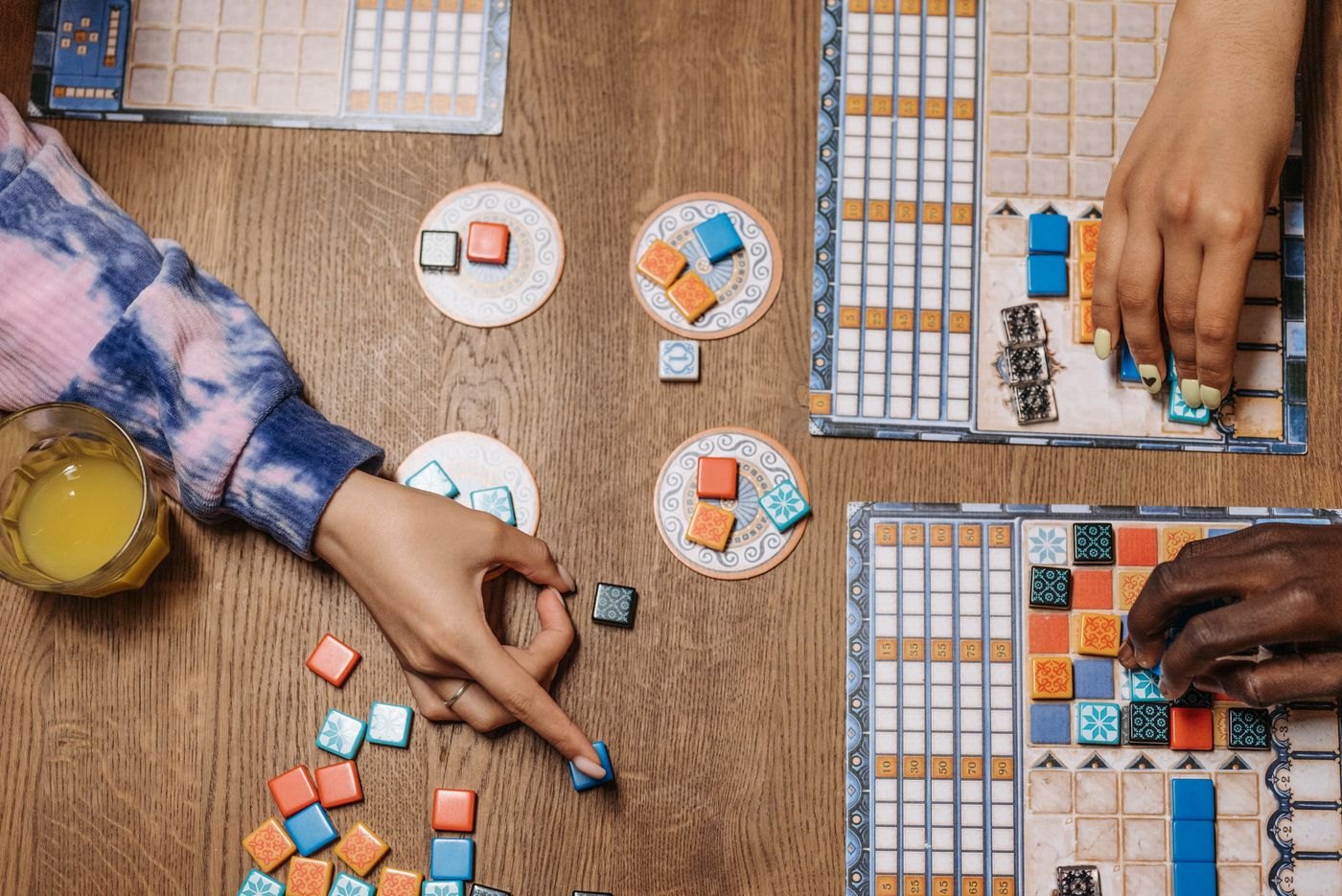 Hands placing coloured tiles on a player board