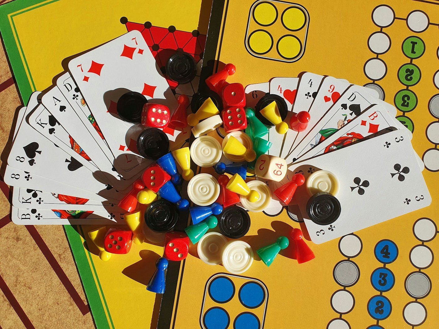 Cards, dice, counters and pawns arranged over a game board