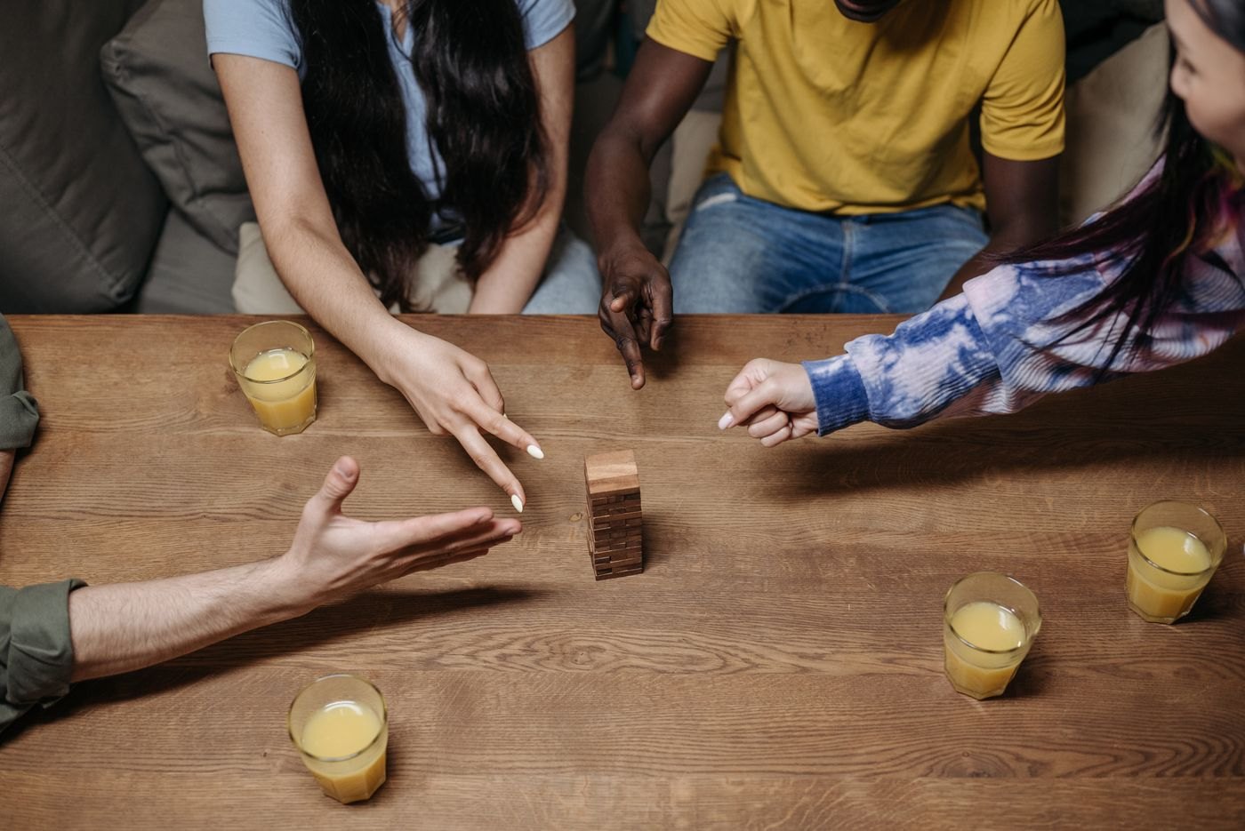 Players gathering their hands around a small wooden stacking tower
