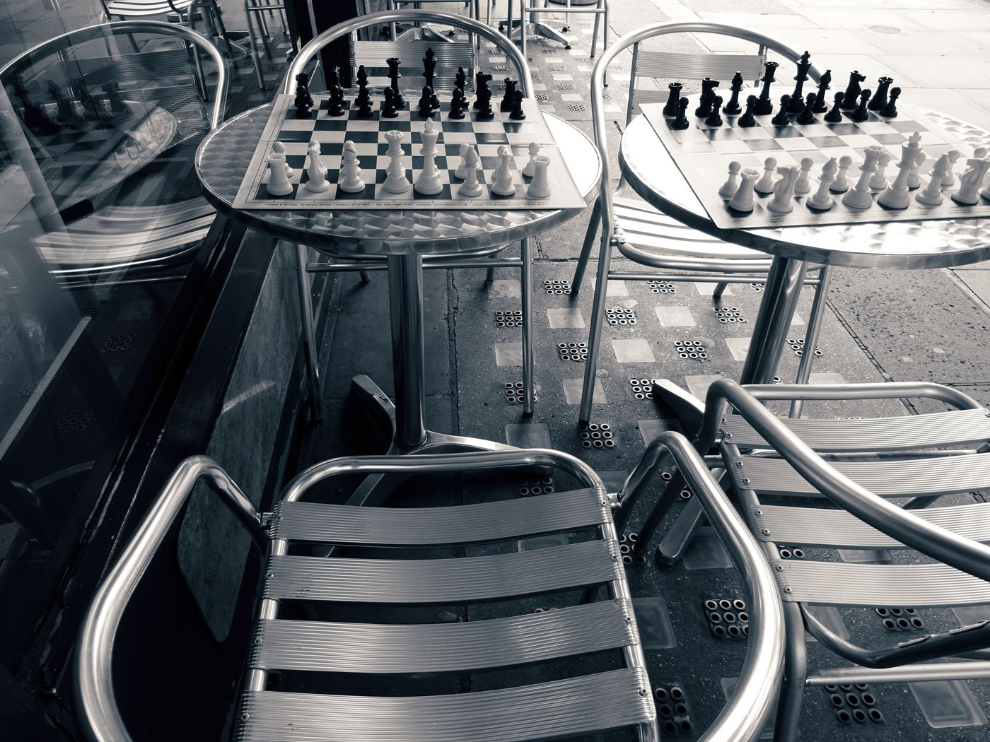 Two separate chess tables arranged side by side with their own seats