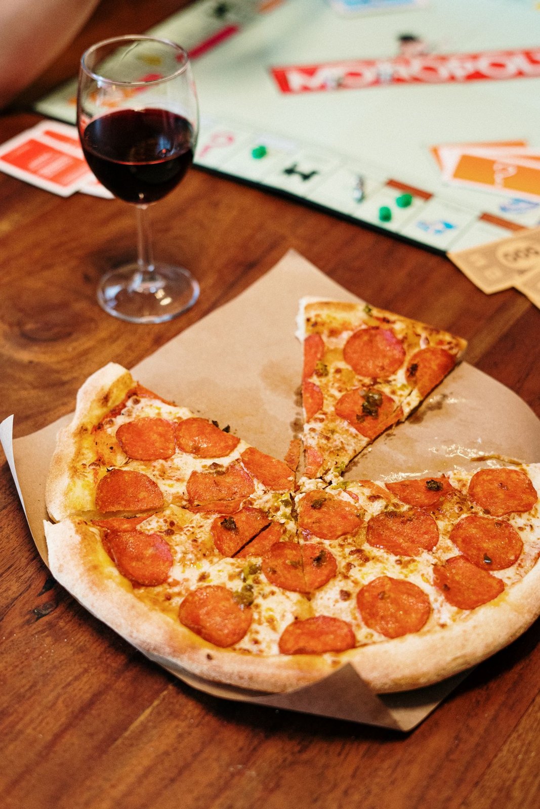 Pizza and a drink beside the edge of a board game