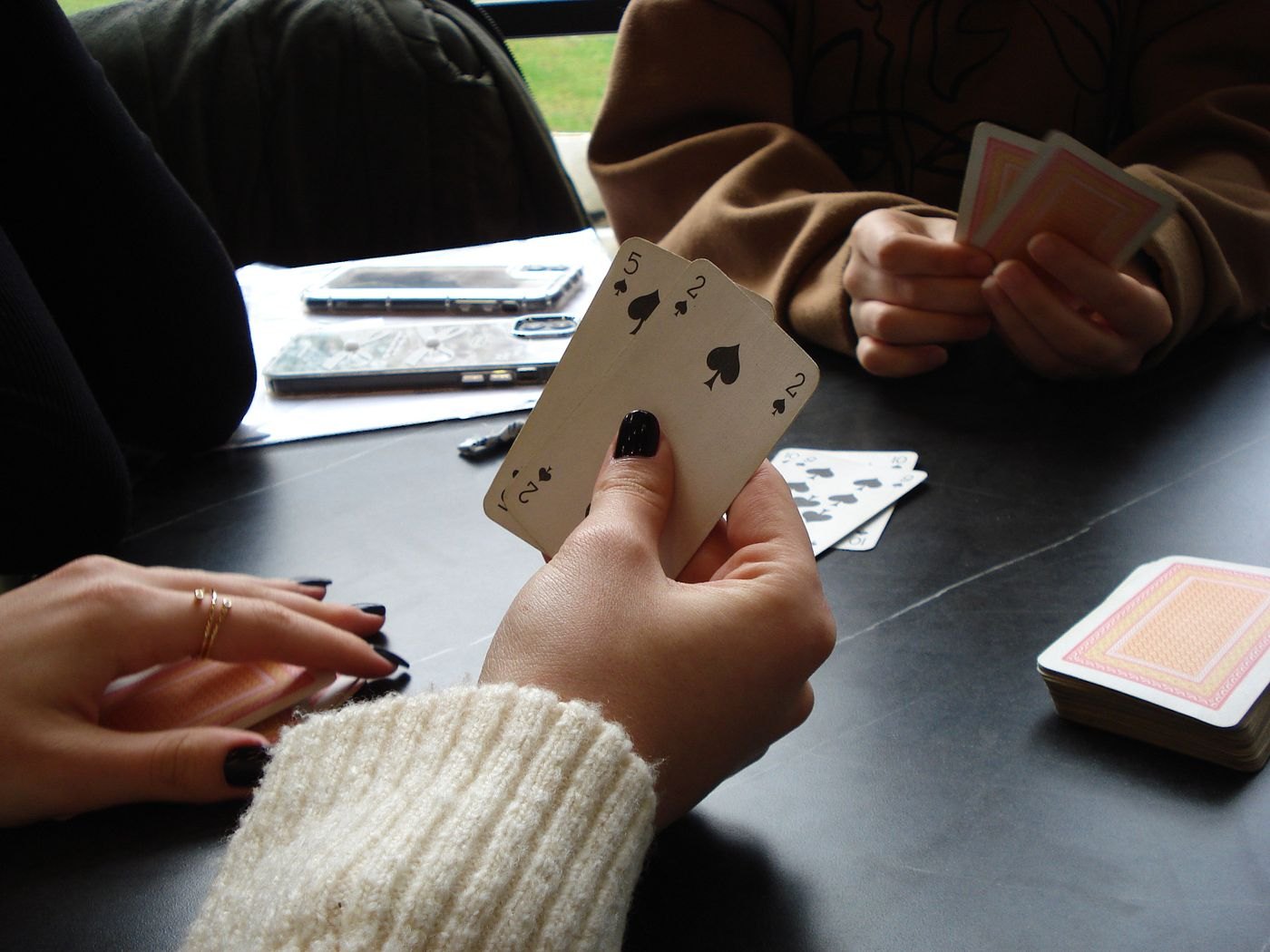 Hands choosing playing cards above a table